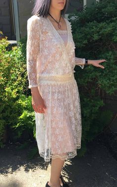 "Lovely Vintage 90's off white lace dress. Sheer see through style. Dare to bare or layer. See that this dress comes with the pink satin lining but we also photographed this with a black slip underneath. (Black slip not included). Measurements for Outer Lace Dress: 14\" Arm 14\" Shoulders 34\" Waist 49\" Length Measurements for Pink Satin Lining: 32\" Bust and Waist 49\" Length" Feminine Scalloped Lace Dress For Wedding Guest, Feminine Lace Patchwork Dress For Wedding Guest, Feminine Lace Trim Dress For Wedding Guest, Beige Lace Dress With V-neck, Feminine Lace Top Wedding Dresses, Elegant Lace Dress With Scalloped Lace For Wedding Night, Elegant Lace Dress With Lace Trim For Wedding Night, Elegant Sheer Lace Dress For Wedding, Elegant Scalloped Lace Dress For Wedding Night