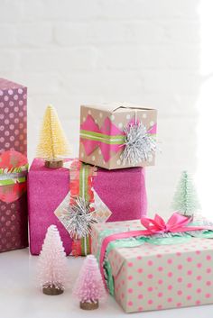 presents wrapped in pink, green and white paper with christmas trees on the top are sitting next to each other