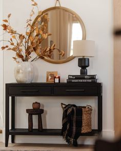 a table with a mirror, lamp and vase on it