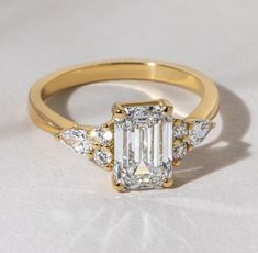 an emerald cut diamond ring with three pear shaped diamonds