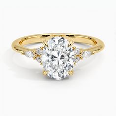 a yellow gold engagement ring with an oval cut diamond and side stones on the band