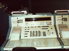 two old electronic devices sitting next to each other on top of a desk in a room