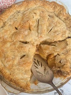 a pie with a slice missing from it on a glass plate next to a spoon