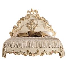 a white bed with gold trimmings and pillows on it's headboard