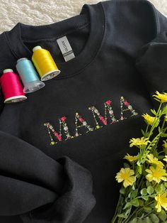 some spools of thread sitting on top of a black shirt with the word mama