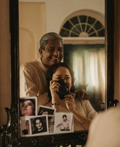 a man and woman taking pictures in front of a mirror