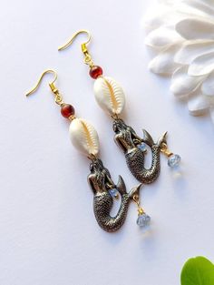 These  feature: ~ White cowrie shells ~ Vintage Carnelian beads ~ Teardrop blue quartz beads ~ faceted blue glass crystals ~ 1.4 x 1 inch sterling silver plated (over brass) Mermaid charms  ~ Gold plated ear wire hooks ~ They are 3 inches long.  Thanks for shopping with JewelryByOri! ~ Shop more Cowrie Jewelry from JBO here: https://www.etsy.com/shop/JewelryByOri?ref=seller-platform-mcnav&search_query=Cowrie Beach Dangle Beads Jewelry, Beaded Teardrop Jewelry For The Beach, Teardrop Beaded Jewelry For The Beach, Handmade Mermaid Jewelry For Beach, Teardrop Dangling Beads Jewelry For Beach, Handmade Mermaid Beach Jewelry, Beach Jewelry With Teardrop Dangling Beads, Beach Teardrop Jewelry With Dangling Beads, Bohemian Shell Earrings For Jewelry Making