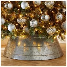 a christmas tree in a metal bucket with ornaments on the top and lights around it