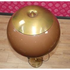 a brown and gold lamp sitting on top of a wooden floor next to a pink wall