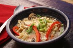 a bowl filled with pasta and veggies on top of a red napkin next to a spoon