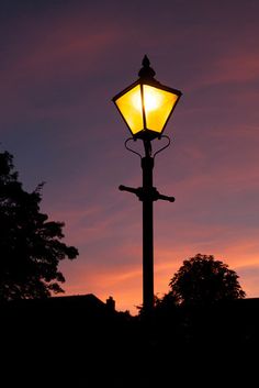 a street light with the sun setting in the background