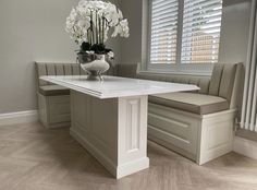 a vase with white flowers sitting on top of a table next to a bench in a room