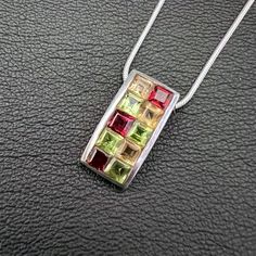 SKU: SP-016-BMaterial: 925 stamped sterling silverGemstone(s): Garnet, Citrine and PeridotGemstone Dimensions: 20 X 10 X 3 mmWeight: 4.4 gramsThis cheery arched rectangle pendant features two rows of multi-colored princess-cut gemstones within the rectangle. The gemstones are Garnet, Citrine and Peridot. This is a fun piece, reminiscent of a colorful chocolate bar! The pendant comes with a 18 inch sterling silver-plated snake chain. If you require a longer, shorter or different chain, simply inc Colorful Chocolate, Rectangle Pendant, Peridot Gemstone, Peach Moonstone, Blue Lace Agate, Lace Agate, Chocolate Bar, Snake Chain, Sterling Silver Pendant