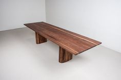 a long wooden table sitting on top of a white floor next to a wall in a room