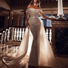 a woman in a white dress standing on a balcony next to a chandelier