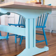 a kitchen table with two blue chairs and a wooden counter top in the middle of it