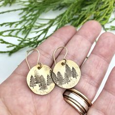 "Tree Earrings - Winter Earrings - Forest Earrings - Brass Gold Earrings - Gift for her - Stocking Suffer - Pine Earrings A little forest for your ears.... 5/8\" brass disks are stamped with little pine trees, and given a rustic finish. They hang from hand formed gold filled earwires. The earrings dangle about 1\"." Nickel-free Round Nature-inspired Earrings, Nature-inspired Nickel Free Round Earrings, Nickel-free Nature-inspired Earrings As Gift, Nature-inspired Hoop Earrings As Gift, Nickel-free Nature-inspired Earrings For Gift, Nature-inspired Round Hoop Earrings For Gift, Nature-inspired Everyday Jewelry With Matching Earrings, Personalized Sterling Silver Earrings As Gift, Personalized Drop Earrings As A Gift