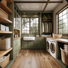 a washer and dryer in a room with green cabinets, wood flooring and open shelving