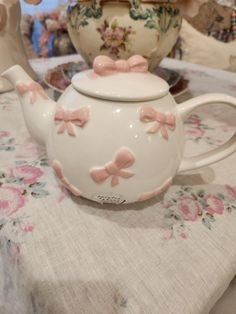 a teapot with pink bows on it sitting on a table next to other items