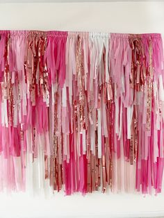 pink and gold streamers hanging on the wall in front of a white wall,