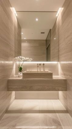 a bathroom with a sink, mirror and vase on the counter top in front of it