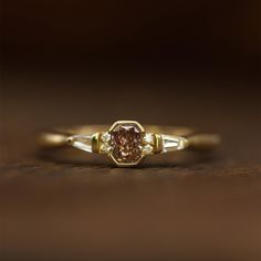 a close up of a ring with a brown diamond in it on a wooden surface