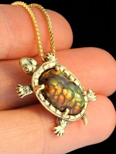 "\"Sylvester Tortoise\" Pendant is a one of a kind design cast in 18K gold. A 5 carat Fire Agate is the shell for this miniature tortoise pendant. The green, orange and gold iridescence of the fire agate makes a plate like pattern, reminiscent to the plates on a turtle or tortoise shell and the bottom of the shell is carefully etched with the plate pattern. The Tortoise is 1\" long and 5/8\" across.   The stone is 9/16\" high X 3/8\" across.   All Marty Magic Jewelry is packaged in a beautiful box, embossed with the gold foil Marty Magic dragon logo. Perfect for any occasion! Designed in Santa Cruz California by Marty Magic.  Made in the U.S.A." Handmade 14k Gold Oval Cabochon Jewelry, Luxury Polished Bronze Jewelry, Luxury Collectible Bronze Jewelry, Collectible Yellow Gold Necklaces With Gemstone, Unique Yellow Gold Collectible Jewelry, Unique Gold Cabochon Jewelry, Unique Gold Jewelry With Cabochon, Unique High Luster Round Jewelry, Unique Round High Luster Jewelry