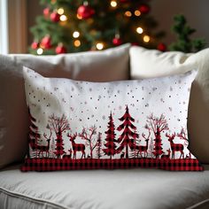 a christmas pillow sitting on top of a couch next to a christmas tree in the background