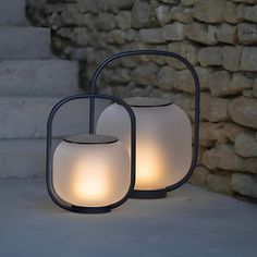 two lamps sitting next to each other in front of some steps and stone wall behind them