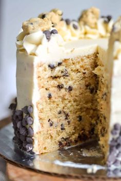 a cake with white frosting and chocolate chips is cut in half on a plate