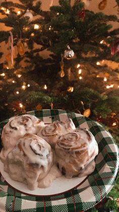 cinnamon rolls on a plate in front of a christmas tree