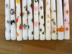 six candles with different designs on them are lined up in a row, one is white and the other is orange