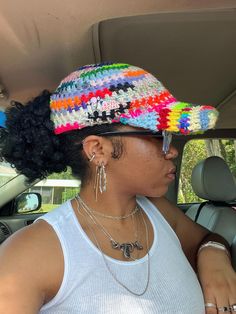 a woman sitting in the back seat of a car wearing a multicolored hat