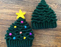 two crocheted christmas trees sitting on top of a wooden floor next to each other