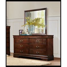 a dresser with a mirror on top of it next to a vase filled with flowers