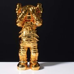 a gold bear statue is standing on a white surface in front of a black background