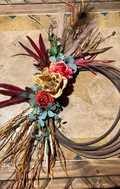 an arrangement of dried flowers and feathers on a table