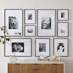 a white wall with many black and white pictures hanging on it's sideboard