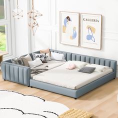 a large blue bed sitting on top of a hard wood floor next to a window