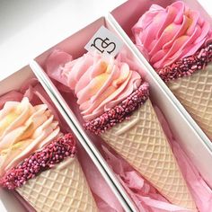 three ice cream cones with sprinkles and pink frosting in a box