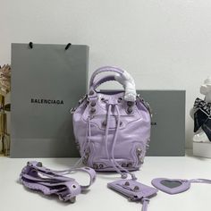 Balenciaga 's popular 'Le Cagole' series is a modern interpretation of its 'City' handbags - reshaped into a bucket bag design to inject a new soul into it. The large size adds two round top handles, combining classic and Modern trends are perfectly integrated. On the basis of retaining the original DNA of the motorcycle bag's flat rivets, delicate buckles and tassel zippers, it adds adjustable woven shoulder straps and a cute and playful heart-shaped mirror, which perfectly softens the neutral Designer Bucket Bag With Handles, Designer Bucket Bag With Detachable Strap, Designer Top Handle Bucket Bag For Shopping, Designer Bucket Bag With Dust Bag For Errands, Designer Bucket Bag For Daily Use, Designer Bucket Bag With Handles For Errands, Designer Bucket Satchel With Handles, Designer Bucket Satchel For Shopping, Designer Bucket Hobo Bag