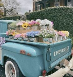 an old blue truck with flowers on the back