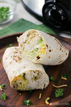 two burritos sitting on top of a wooden plate