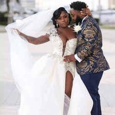 a bride and groom pose for a wedding photo in front of the camera with their arms around each other