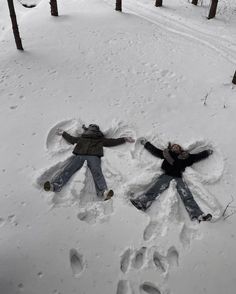 two people are laying in the snow with their arms spread out and feet prints on them