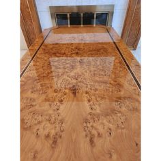 a large wooden table with glass top in front of a fire place and fireplace mantel