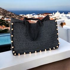 a black purse sitting on top of a white counter next to a window with the ocean in the background