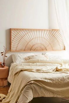 a bed with white sheets and pillows in a bedroom next to a table, rugs and potted plants