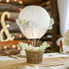 a table topped with a basket filled with flowers and a hot air balloon sitting on top of it