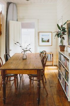 a wooden table sitting in the middle of a living room next to a book shelf